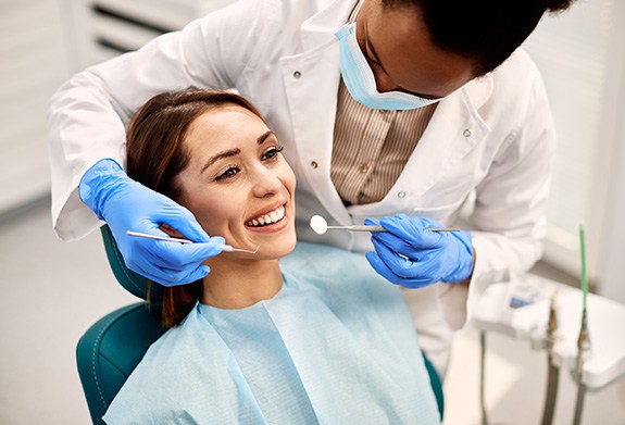 Woman smiling while dentist examines their teeth