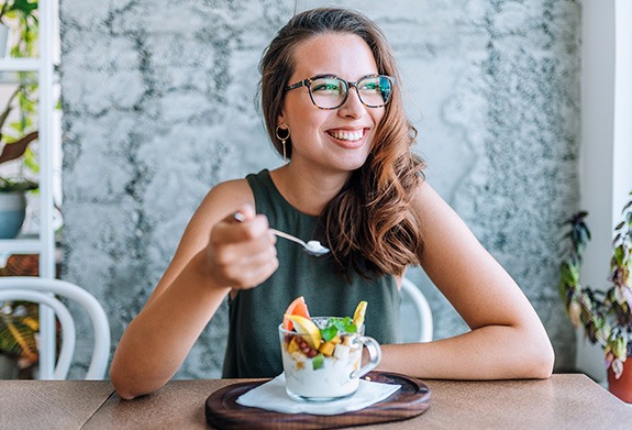 Woman smiling while eating healthy breakfast at home