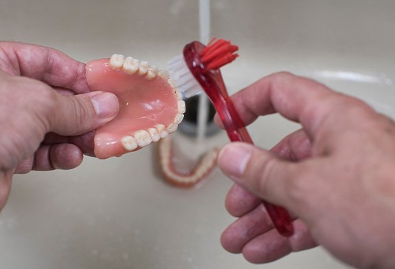 a person cleaning their denture